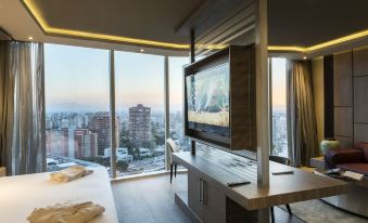 a modern bedroom with a large window offering a city view , a flat - screen tv on the wall , and a comfortable bed at Icon Hotel