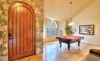 a pool table is set up in a room with a stone wall and wooden door at Arrowhead