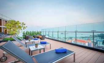 a rooftop patio with a view of the ocean , featuring lounge chairs and a table at Somerset Harbourview Sri Racha