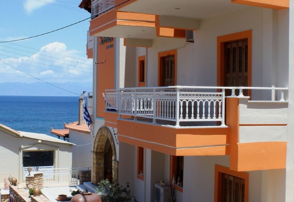 a multi - story building with an orange and white facade is situated on a hillside overlooking the ocean at Sofotel