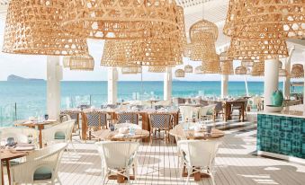 a beach dining area with wooden tables and chairs , creating a relaxing atmosphere for guests at Lux* Grand Gaube