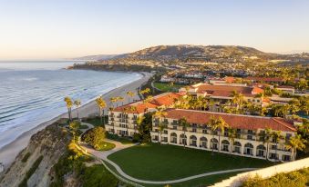 a large white building with red roofs is situated on a cliff overlooking the ocean at The Ritz-Carlton, Laguna Niguel