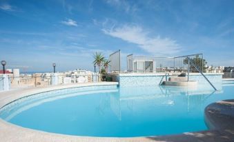a large swimming pool with a blue sky and white buildings in the background , under a clear sky at Sunflower Hotel