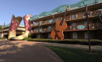 a hotel with a large mural of a cowboy boot and two cello - shaped decorations in front at Disney's All-Star Music Resort