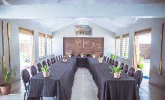 a long table with black tablecloths and potted plants is set up in a room with large windows at Le Life Resort