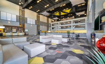 a modern office space with a large open space , white couches , and yellow ceiling lights at Holiday Inn Morgantown - Reading Area