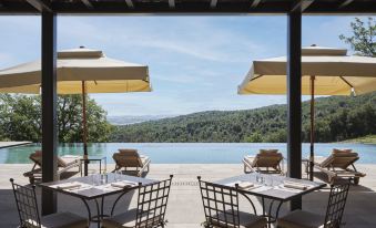 an outdoor dining area with several chairs and tables , providing a pleasant atmosphere for guests to enjoy the view of a lake and mountains at Rosewood Castiglion del Bosco