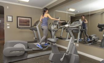 a woman is working out on a treadmill in a gym , surrounded by other people at Hotel Brossard