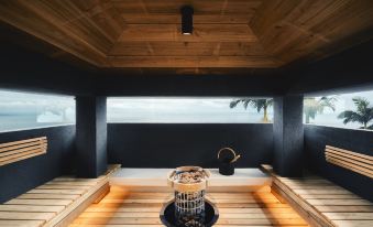 a modern sauna with wooden flooring , large windows , and a view of the ocean through an opening at Sankara Hotel & Spa Yakushima