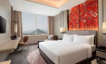 a luxurious hotel room with a king - sized bed , a large window offering a view of the city , and a desk with a laptop at Radisson Lampung Kedaton