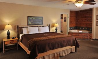 a large bed with a brown comforter is in the middle of a room with a sink and lamp at Boarders Inn & Suites by Cobblestone Hotels – Waukon
