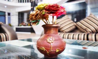 a red vase filled with colorful flowers is sitting on a table in a living room at Hotel President