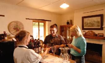 a group of people are sitting at a table , holding wine glasses and talking about the wine at Stone Hut Cottage