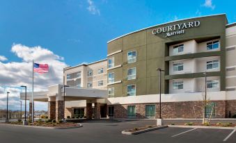 a courtyard by marriott hotel with a large parking lot and american flag in front of it at Courtyard Schenectady at Mohawk Harbor