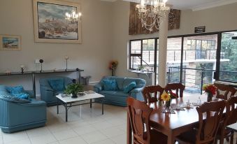 a spacious living room with blue couches , wooden dining tables , and chairs , as well as a large window that overlooks a balcony at Hidden Inn