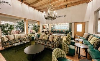 a spacious room with green carpet and furniture , including couches , chairs , tables , and a chandelier at The Cellars-Hohenort
