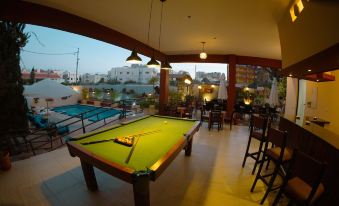a billiards table is set up in a room with large windows and a pool table nearby at Grand Hotel Madaba