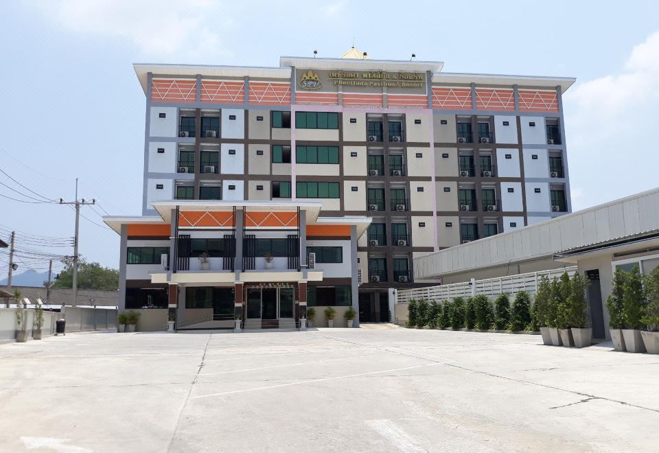 a large , modern apartment building with multiple floors and balconies , situated next to a parking lot at Phetlada Pavilion & Resort