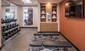 a gym with various exercise equipment , including weights and dumbbells , in a room with a couch and bookshelves at TownePlace Suites Merced