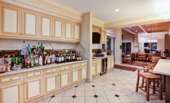 a well - equipped kitchen with wooden cabinets , a dining area , and a television mounted on the wall at Hilton Garden Inn Chesterton
