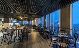 a restaurant with wooden floors and tables , chairs , and a large window overlooking the city at Mercure Hai Phong