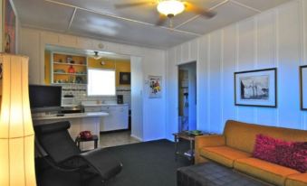 a living room with a yellow couch , black chair , and coffee table under a ceiling fan at Motel Lodge
