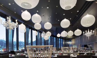 a restaurant with black ceiling and walls , large windows , white hanging lights , and wooden furniture at Scandic Ishavshotel