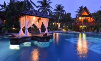 a large outdoor pool with a gazebo and a boat dock , surrounded by palm trees at Tasik Ria Resort