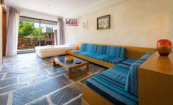 a modern living room with blue sofas , a coffee table , and a window overlooking a balcony at Apollonia Hotel Apartments