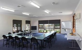 a large conference room with multiple tables and chairs , a projector screen , and windows at Murray Downs Resort