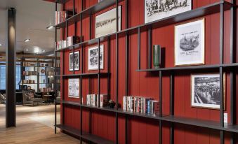 a room with red walls and black shelves filled with books and other items , creating a cozy atmosphere at Canopy by Hilton Ithaca Downtown