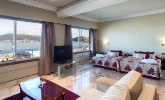 a living room with a couch , chairs , and a tv . the room has a view of the water at Sercotel Hotel Bahia de Vigo