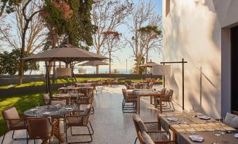 an outdoor dining area with several tables and chairs , umbrellas , and a view of the ocean at Briig Boutique Hotel