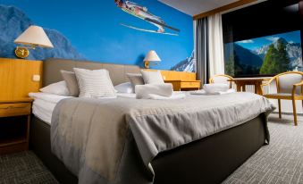 a hotel room with a king - sized bed and a large mural on the wall depicting a snow skiing scene at Hotel Kompas