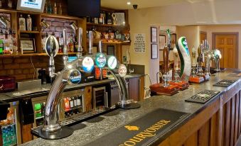a well - equipped bar with several beer taps and a variety of bottles on the counter at The Feathers