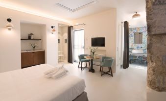 a modern bedroom with a bed , desk , and dining table , as well as a bathroom area with a bathtub at Masseria Amastuola Wine Resort