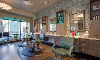 a modern barber shop with multiple mirrors , large windows , and multiple chairs , providing an airy atmosphere at The Mosey Buffalo Williamsville, Tapestry Collection by Hilton