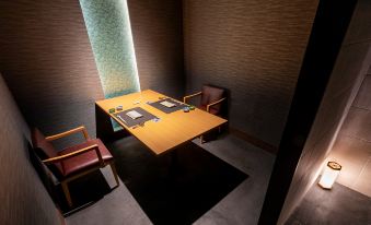 a wooden dining table with two chairs and a window , situated in a dimly lit room at The Lake View Toya Nonokaze Resort