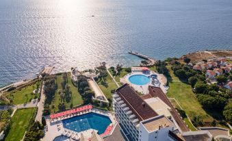 a large hotel complex with multiple swimming pools , sun loungers , and other amenities near the ocean at Grand Hotel Ontur Cesme