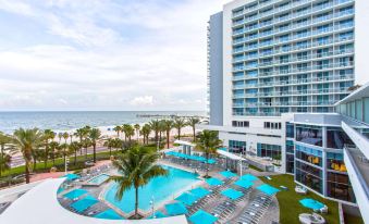 a large hotel with a swimming pool and palm trees , overlooking the ocean and beach at Wyndham Grand Clearwater Beach