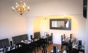 a restaurant with black chairs and tables , a chandelier , and a large mirror hanging on the wall at Canterbury Hotel