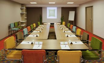 a conference room with a long table and chairs , each chair has a colorful chair at Ibis Styles Chaumont Centre Gare