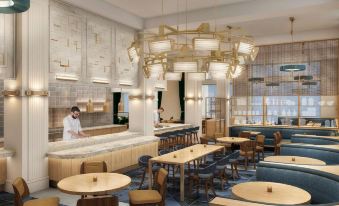 a modern restaurant with a bar , dining tables , and chairs , as well as a chef preparing food in the background at Canopy by Hilton Philadelphia Center City