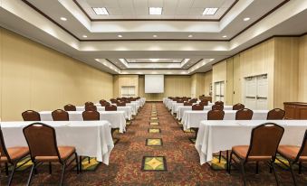 a large conference room with rows of tables and chairs , all facing a projector screen at Hilton Garden Inn Bartlesville