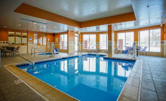 an indoor swimming pool with a blue tiled floor , surrounded by windows that provide ample natural light at Hilton Garden Inn Kankakee