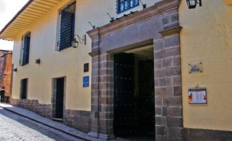 a yellow building with a black door and windows is located on a cobblestone street at Novotel Cusco