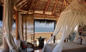 a cozy bedroom with a view of the ocean through a large window , providing a beautiful and serene atmosphere at Villa del Faro