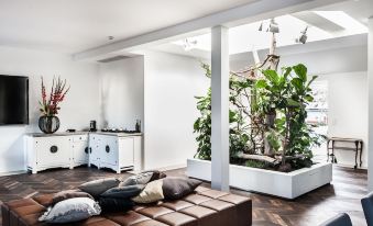 a modern living room with a large couch , coffee table , and plants in a white room at Hotel Weitzer Graz