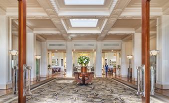 a grand hotel lobby with high ceilings , white columns , and a large vase filled with flowers on the floor at Hyatt Hotel Canberra - A Park Hyatt Hotel