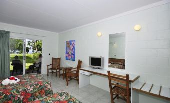 a modern , minimalist living room with white walls and wooden furniture , including a couch , chairs , and a dining table at Kosrae Nautilus Resort